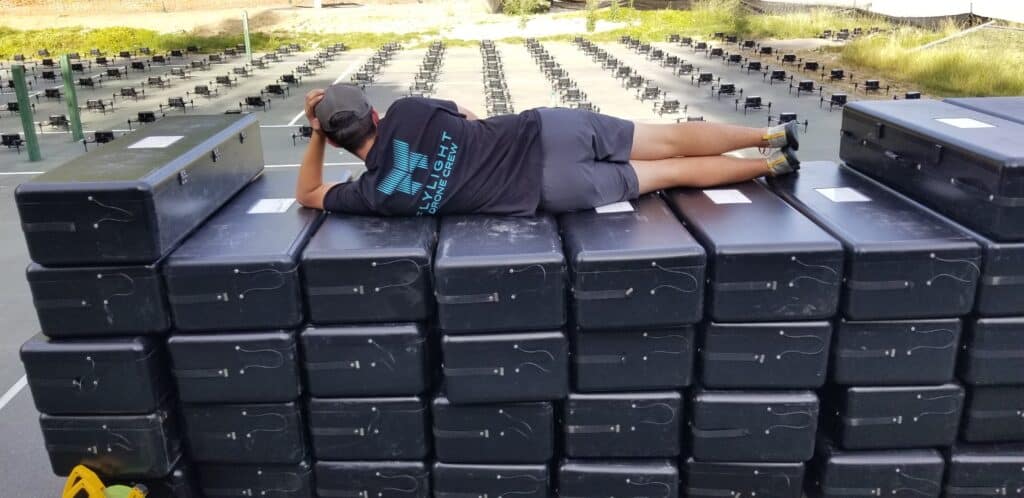 Man lying on top of stacked black cases outdoors