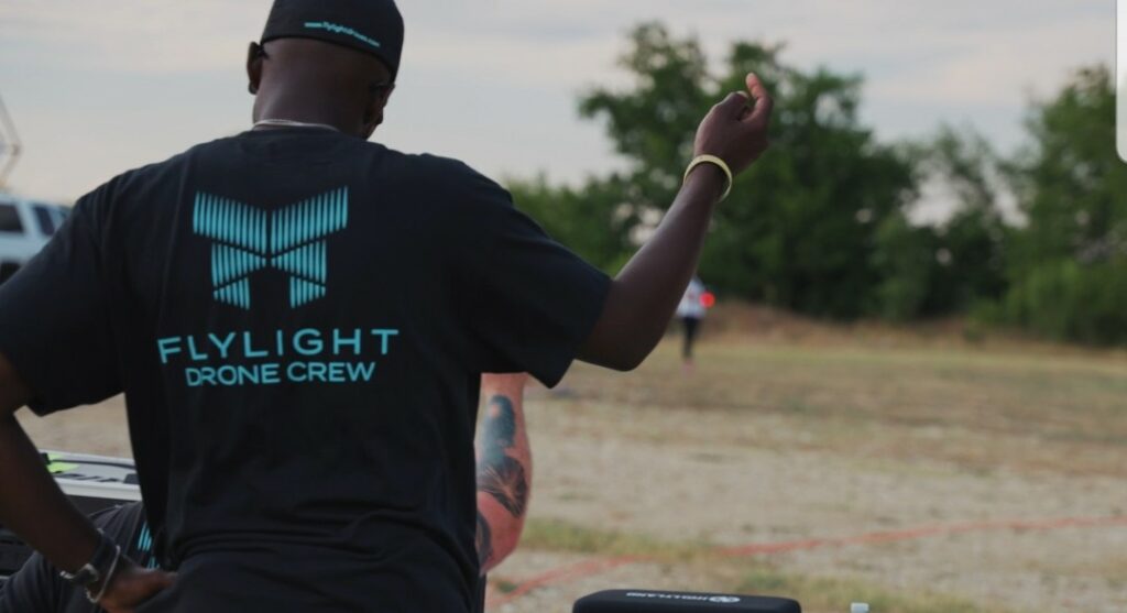Man in Flylight Drone Crew shirt piloting a drone