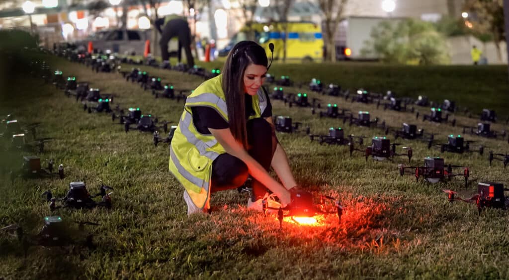 Woman adjusts drone at nighttime outdoor drone showcase