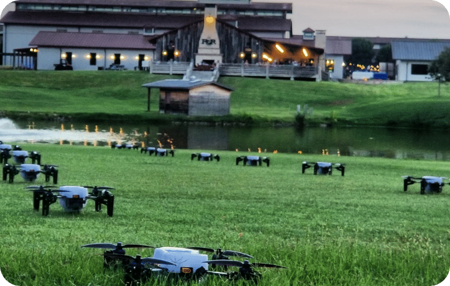 Drones on grass near building and pond at dusk