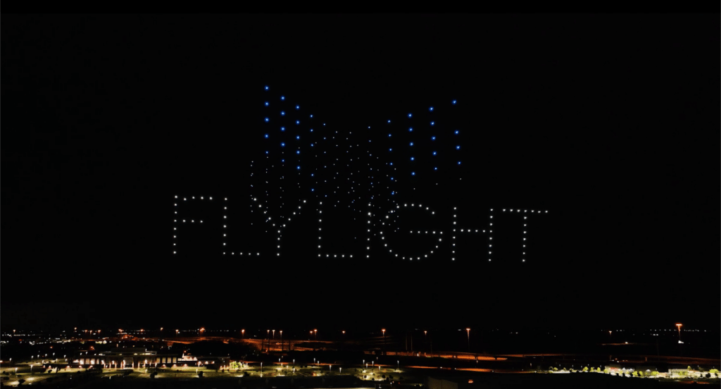 Drone light show spelling 'FLYLIGHT' at night