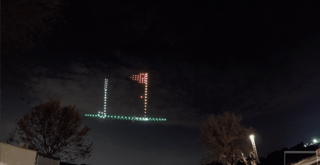 Drone light show displaying L and T shapes at night