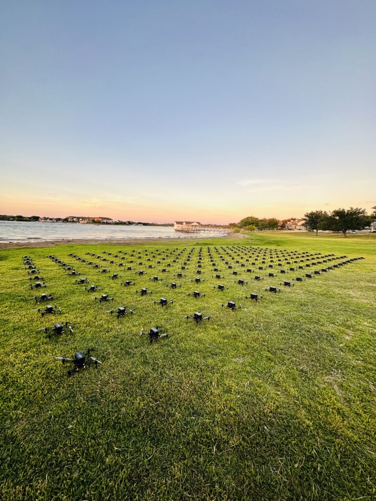 Rows of drones on grass field at sunset near lake